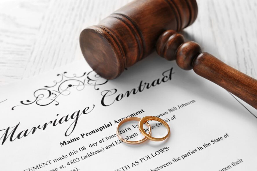 Preparing To Draft A Will - Golden wedding rings with judge gavel on marriage contract, closeup