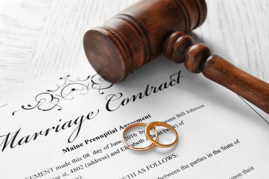 Preparing To Draft A Will - Golden wedding rings with judge gavel on marriage contract, closeup